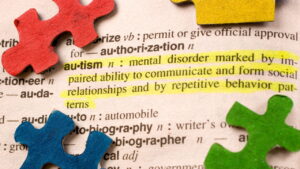 Puzzle pieces on sitting on dictionary open to "Autism" definition