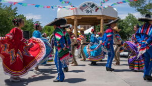 Colourful mexican men and women in traditional dress dancing