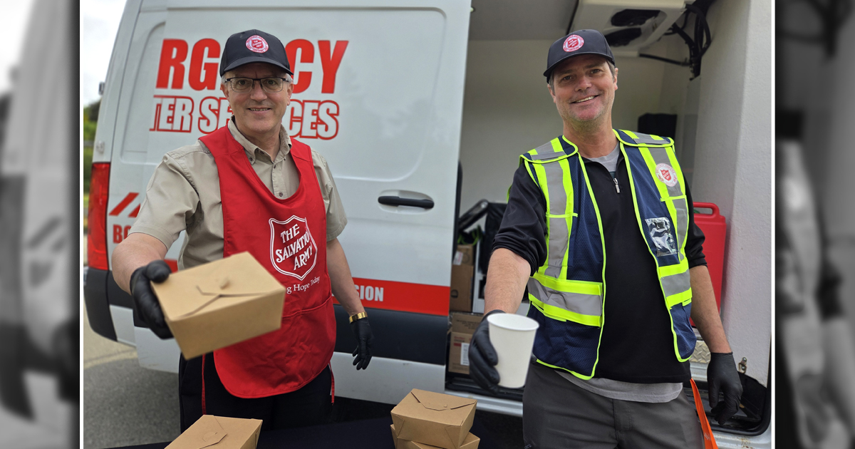 Two men hold out a food box and paper cup 