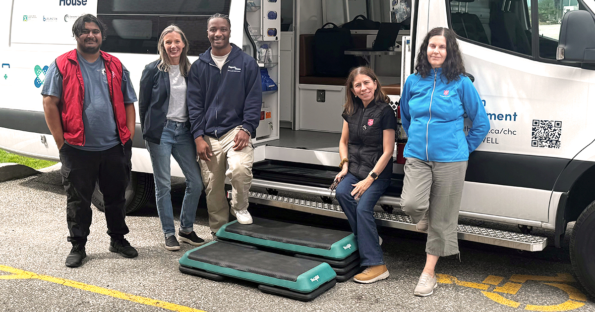 Five people stand by a van