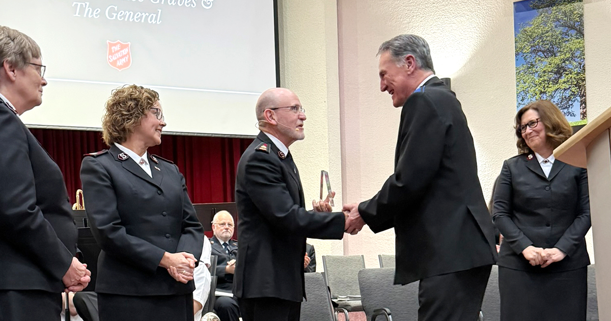 A man shakes hands with another man, while three women look on