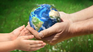 Adult hands holding a globe passing it to a child's hands