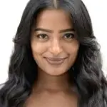 Light brown skinned woman head and shoulders with long black hair smiling